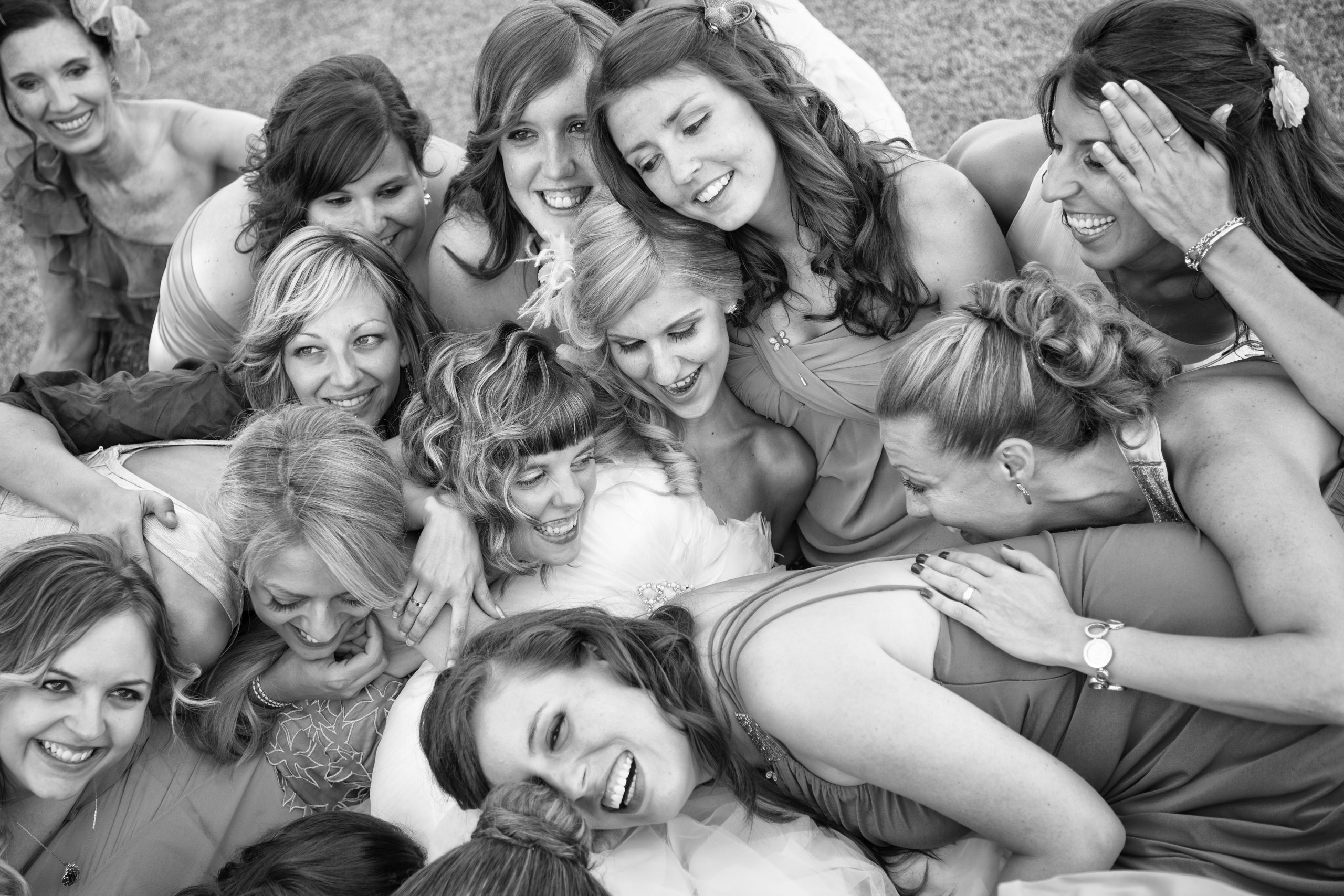 Fotografía divertida de novia con todas sus amigas agolpadas unas encima de otras. La fotografía es en blanco y negro.